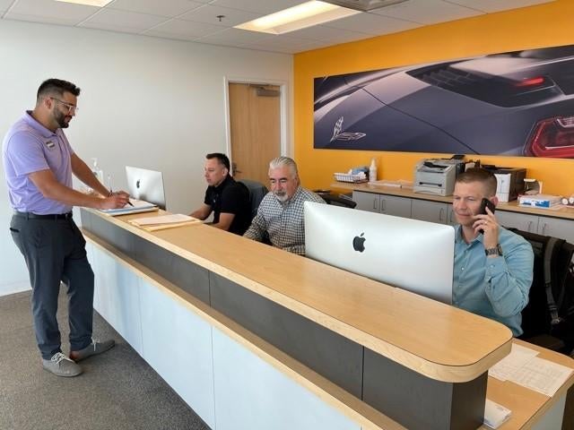 image of a man at a service counter with 3 other men behind desks